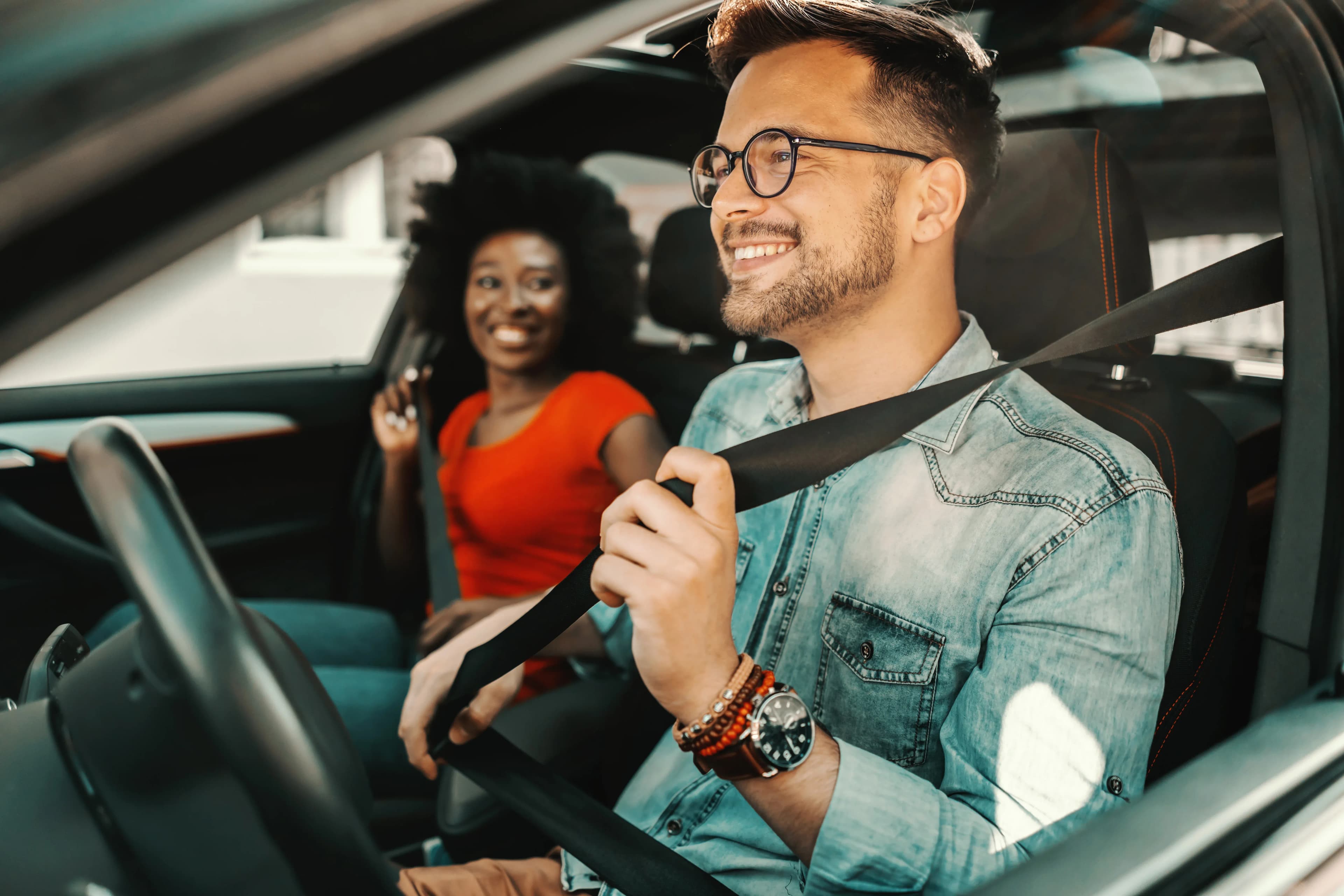 Man and women in car clipping seatbelts